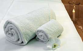 Zwei gerollte weisse Handtuecher mit Orchidee