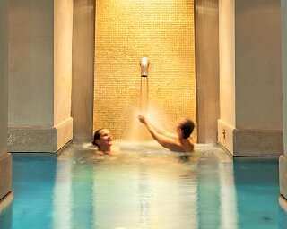 Zwei Personen geniessen die Nackendusche vor der Goldwand