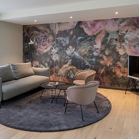 Graues Sofa in Guesthouse vor stylischer farbiger Tapete