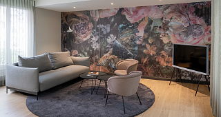 Graues Sofa in Guesthouse vor stylischer farbiger Tapete